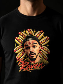 Close-up of The Raven Hotdogs tee chest print: Raven portrait in a backwards cap with a mustard hotdog halo and red The Raven lettering