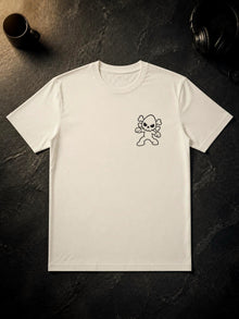 Ivory Nephy Comic Book Collage T-shirt (Tultex 202) laid flat on dark slate, front side up, with the small 3.75 in Nephy skull mascot print on the left chest