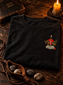 Black Nephilim Slayer David vs Goliath graphic tee folded beside a sling and stones, Fear Is Faith in Evil left chest print