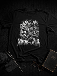 Black Grandma-Maxxing spiritual warfare T-shirt styled flat lay with knitting needles, yarn, reading glasses and a worn Bible