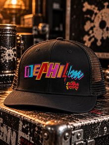 Miami Nephilim embroidered trucker hat in black with black mesh back, multicolor NEPHILIM wordmark and red skull patch on the front