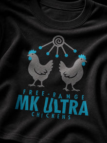 Close-up of the teal and grey MK Ultra Chickens print on a black T-shirt: two hens, radiating antenna and FREE-RANGE MK ULTRA CHICKENS text