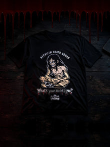 Black NDS What's Your Blood Type? Tee laid on a dark wooden floor in a horror-movie scene: blood dripping from above, a red glow, and a laptop glowing cold blue with the NDS skull on screen. The tee's print shows NEPHILIM DEATH SQUAD over a grinning long-haired creature at a laptop, the dripping red What's your blood type? headline and a cream skull and crossbones