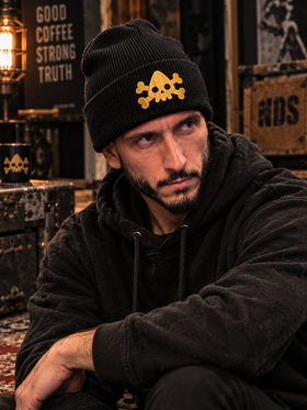 Man wearing black NDS beanie with yellow embroidered skull logo