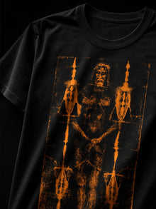 Close-up of the burnt orange Shroud of Turin print on a black T-shirt, face and ornamental bars detail