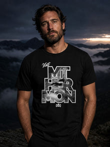 Man wearing the black Visit Mt. Hermon T-shirt by Nephilim Death Squad on a misty mountain ridge at dusk