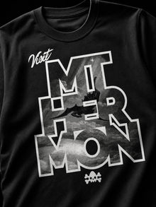 Close-up of the Visit Mt. Hermon print: script Visit above block letters MT HER MON with black-and-white Watchers falling through and a small skull